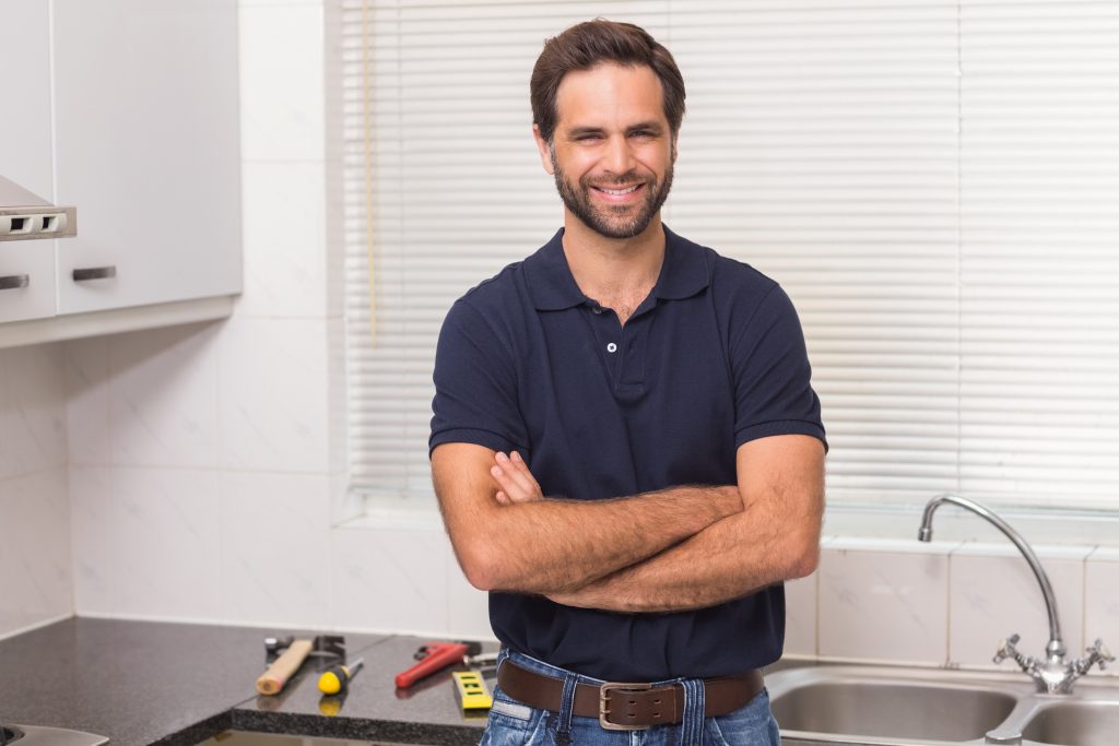 Plumber smiling at the camera in the kitchen