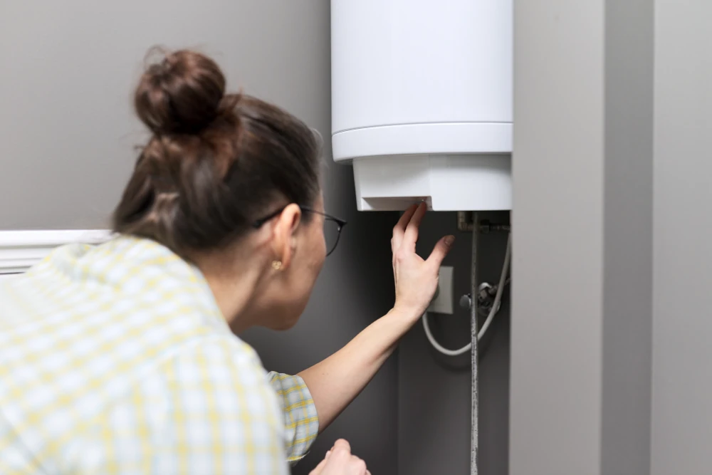 Woman adjusting temperature on a tankless water heater.